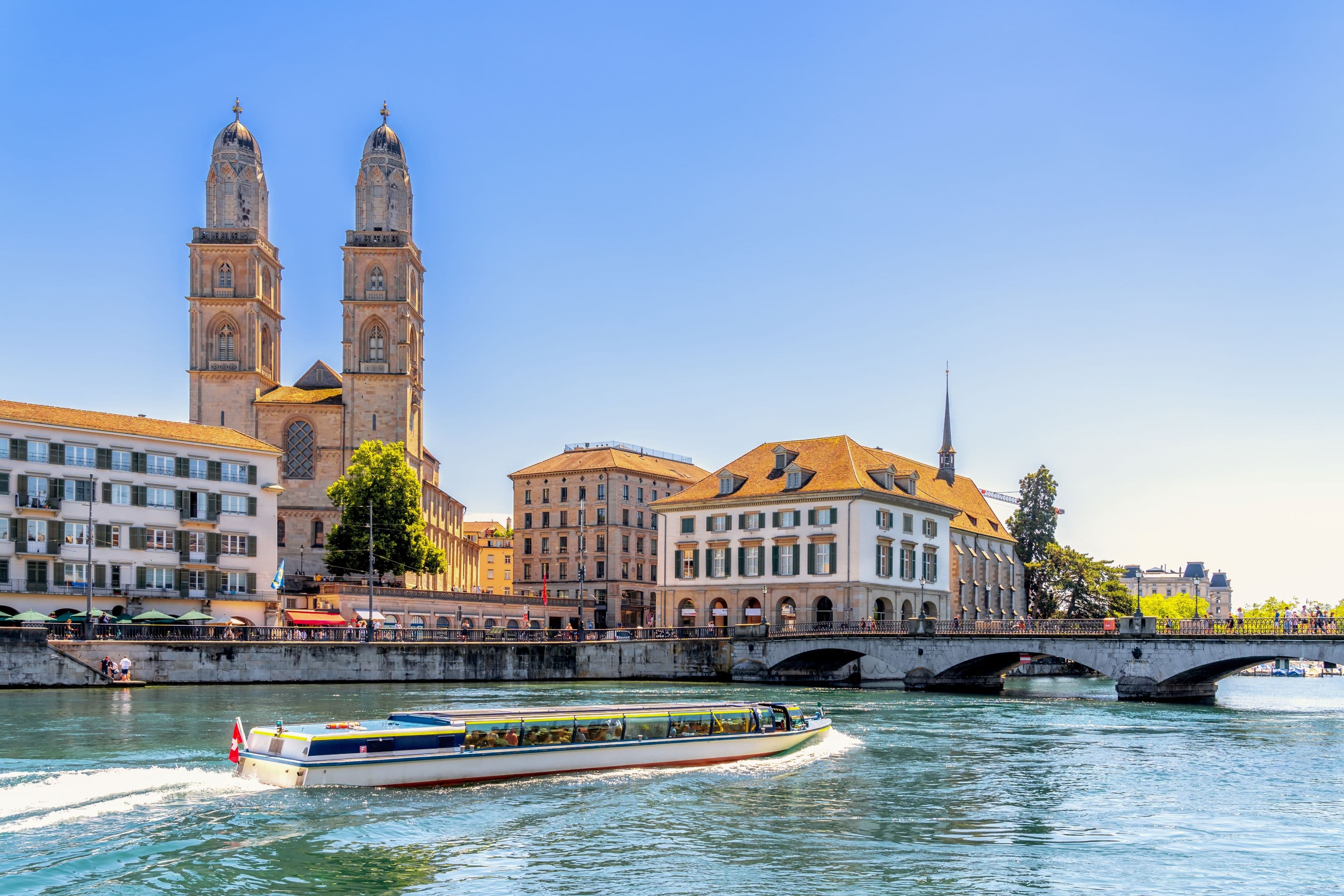 Grossmünster cathedral and Limmat river with boat on a Zurich walking tour in summer