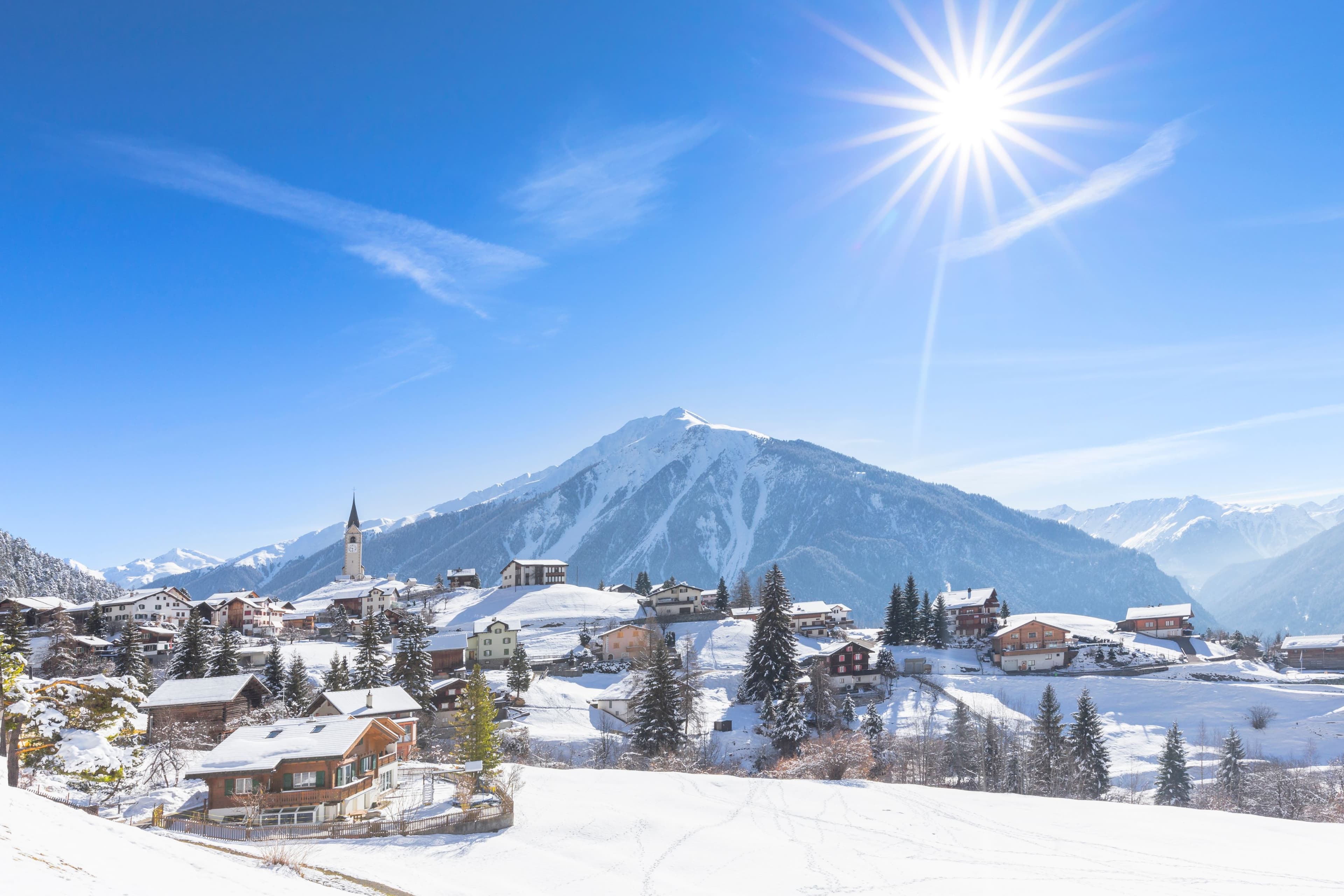  Snow covered alpine village near St Moritz Switzerland with church tower and mountain backdrop