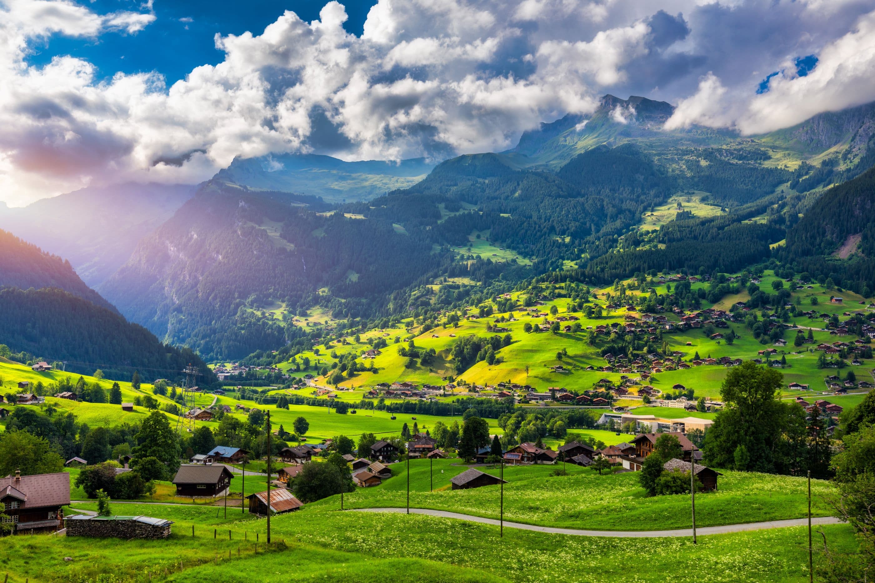 Green alpine valley with wooden chalets near Giessbach Falls Switzerland